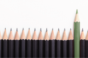 A row of pencils, with a single green pencil poking out above the rest
