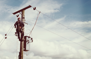 A utility worker at the top of an electric pole