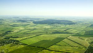 An aerial photo of open green fields and plots of land