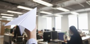 A worker prepares to throw a paper airplane in an office