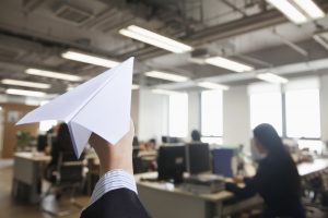 Person holding a paper airplane inside of an office