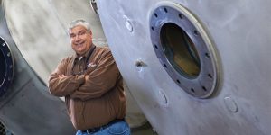 Chris Girtz standing beside heavy industrial equipmment