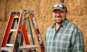 Farm owner standing next to a ladder.