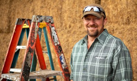 Farm owner standing next to a ladder.