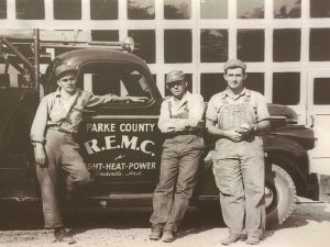 Historical photo of three men standing in front of a truck